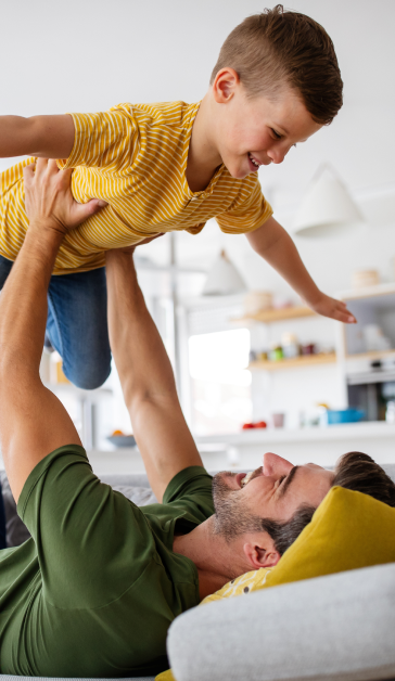 Father and his son playing on the bed.