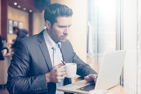 Hombre en su computador con un café