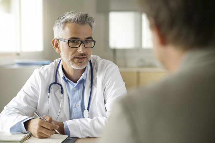 Doctor explicando al paciente cuáles son los niveles normales de LDH en un análisis de sangre.