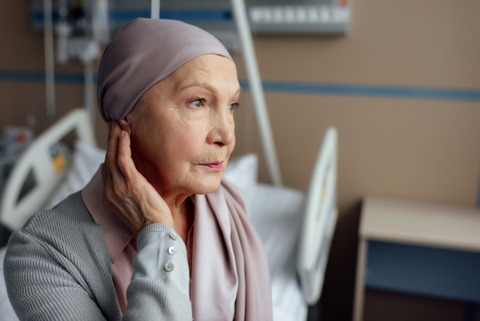 Mujer mayor con cancer sentada en la cama de hospital