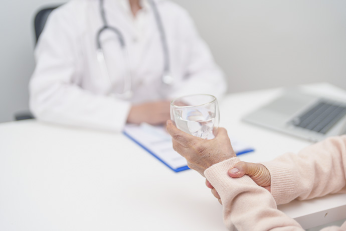 Persona explica al médico síntomas del temblor de manos