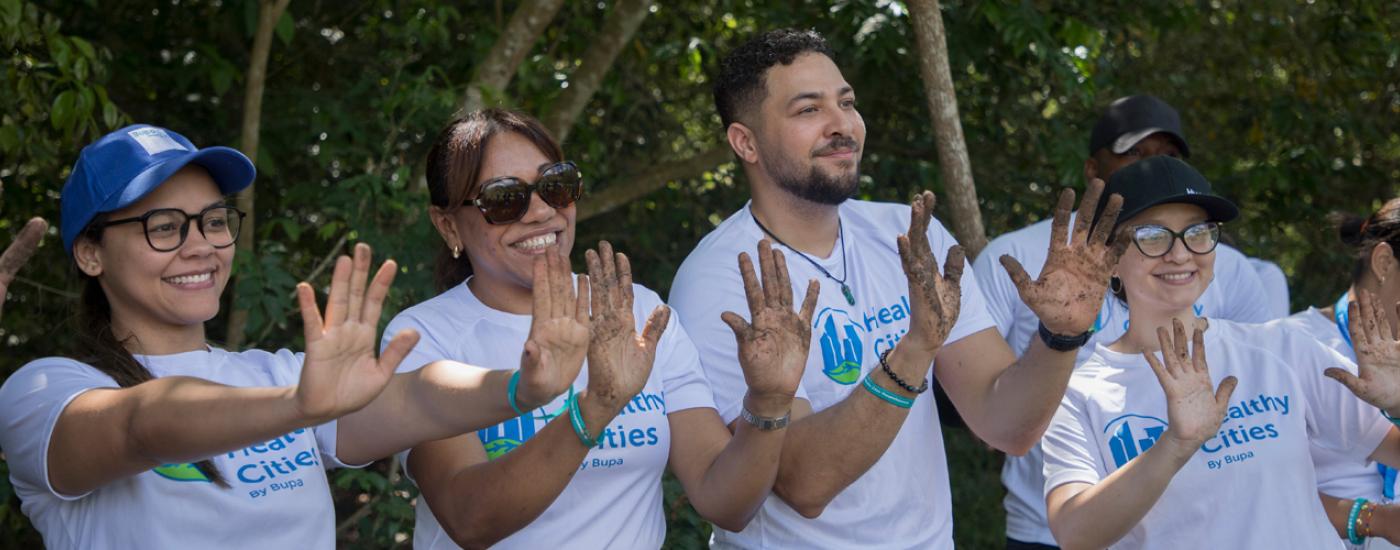 Equipo de Bupa mostrando sus manos sucias despues de plantar árboles
