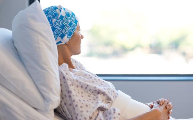 Mujer con cáncer tumbada en cama de hospital