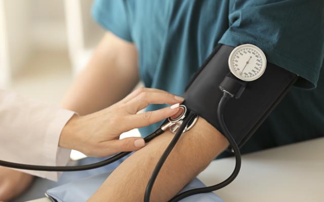 Paciente midiendo su presión arterial y pulso para comprobar sus valores en la tabla de presión arterial.