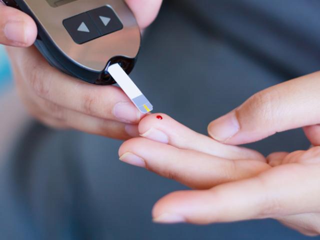 Persona midiendo sus niveles de glucosa con un glucómetro para identificar un posible pico de glucosa.