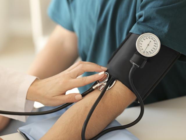 Paciente midiendo su presión arterial y pulso para comprobar sus valores en la tabla de presión arterial.