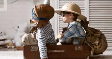 Niños jugando a viajar en avión dentro de una maleta
